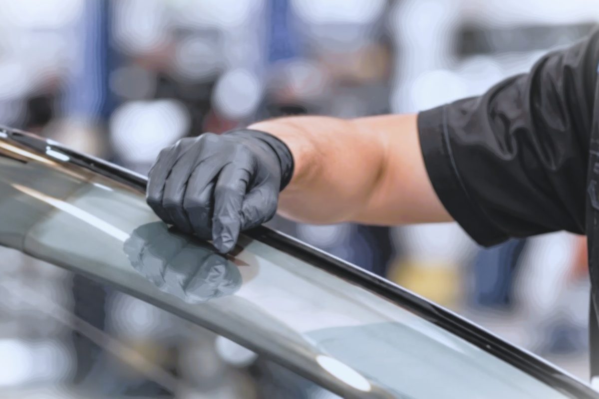 Our technician in gloves checking the edge of a windscreen in the workshop