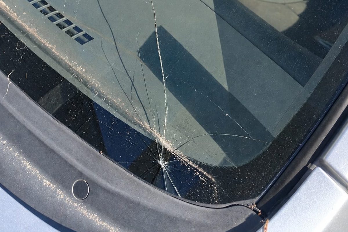 Windscreen with a stone chip and cracks spreading across the glass