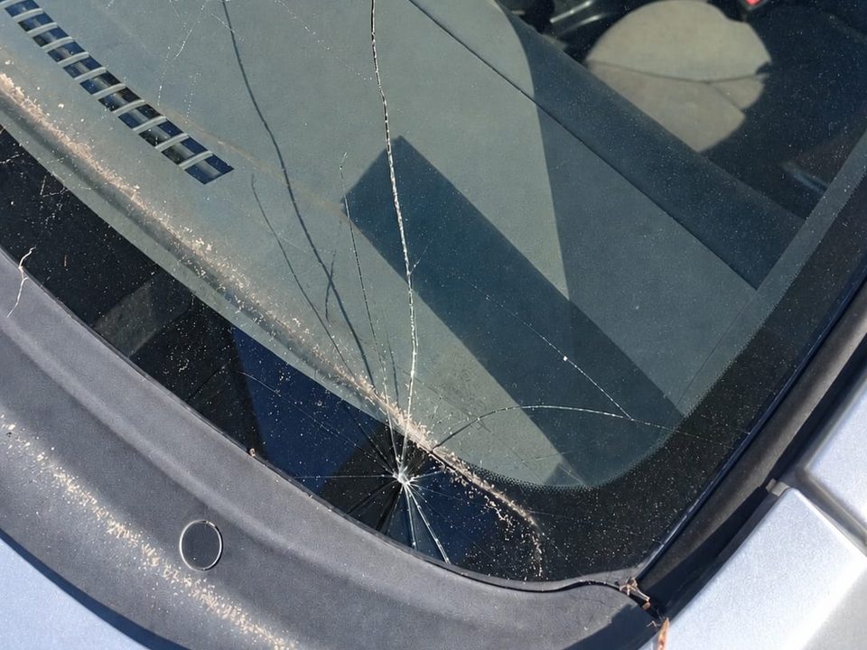 Windscreen with a stone chip and cracks spreading across the glass